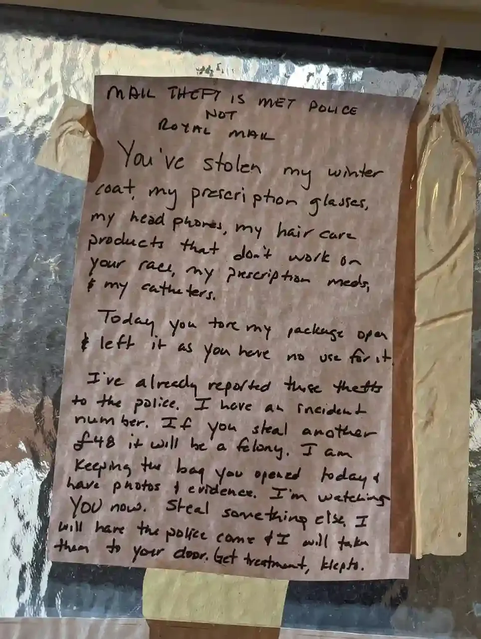 A sign that reads `MAIL THEFT IS MET POLICE NOT ROYAL MAIL. You've stolen my winter coat, my prescription glasses, my headphones, my hair care products that don't work on your race, my prescription meds & my catheters. Today, you tore my package open & left it as you have no use for it. I've already reported these thefts to the police. I have an incident number. If you steal another 48 GBP, it will be a felony. I am keeping the bag you opened today & have photos + evidence. I'm watching YOU now. Steal something else. I will have the police come & I will take them to your door. Get treatment, klepto.`