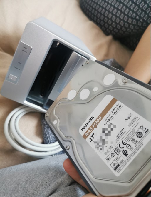 A photo of a Toshiba N300 3.5 inch Hard Drive being inserted into a Silver 2 drive NAS