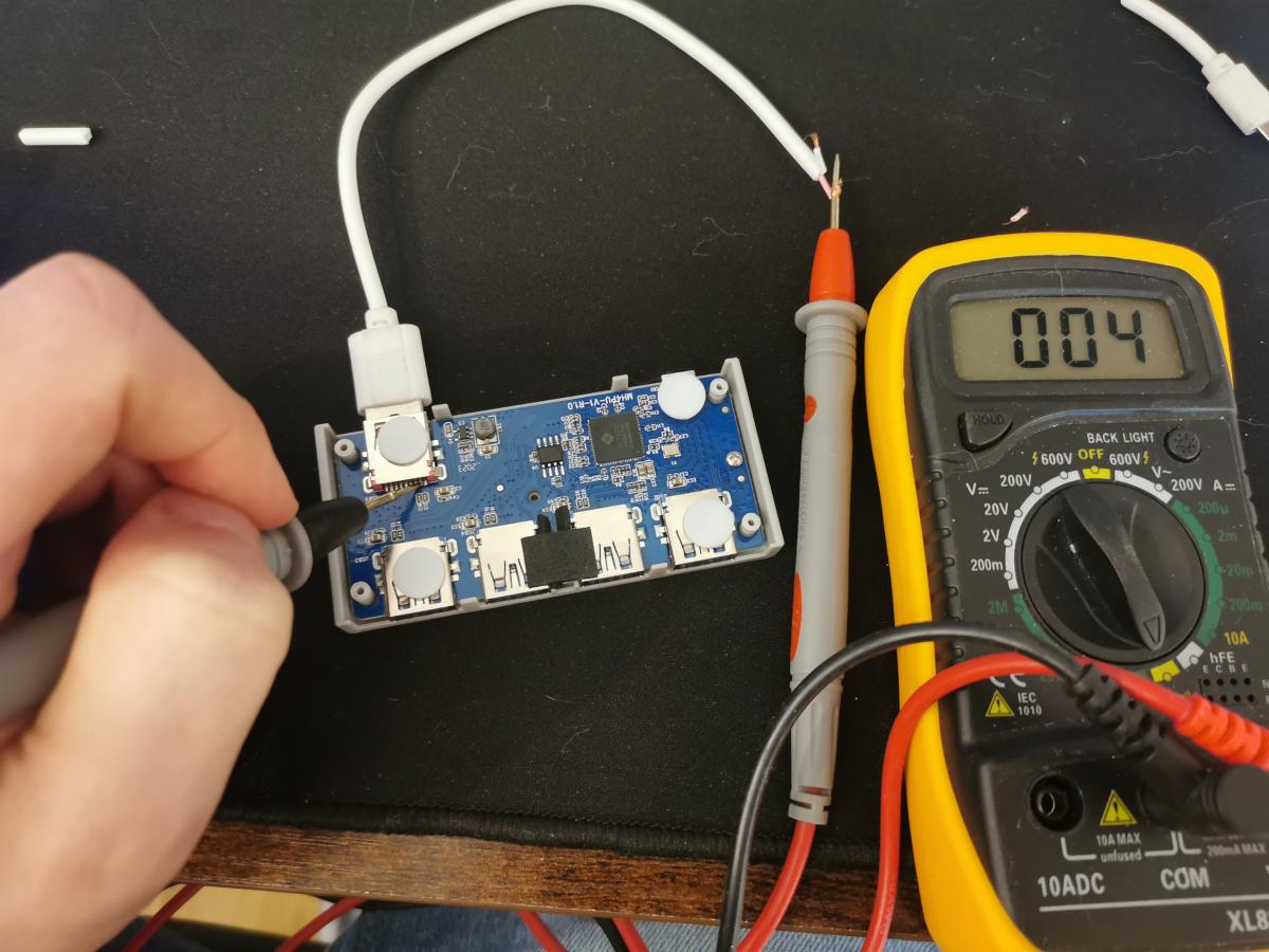 A photo of Kevin measuring the USB pins inside the USB hub with a yellow multimeter